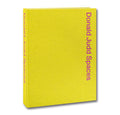 Open page from Donald Judd Spaces art book by Judd Foundation, featuring photographs and illustrations of Judd's minimalist designs.